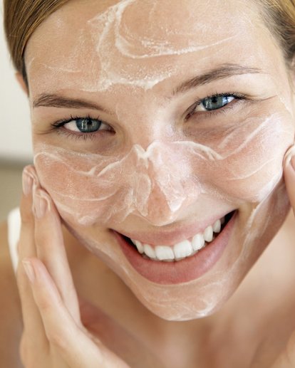 volto di una donna che si spalma la crema sul viso
