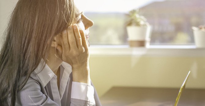 una persona che si copre il viso con la mano.