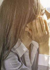 una persona che si copre il viso con la mano.