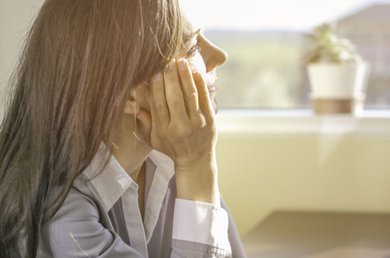 una persona che si copre il viso con la mano.