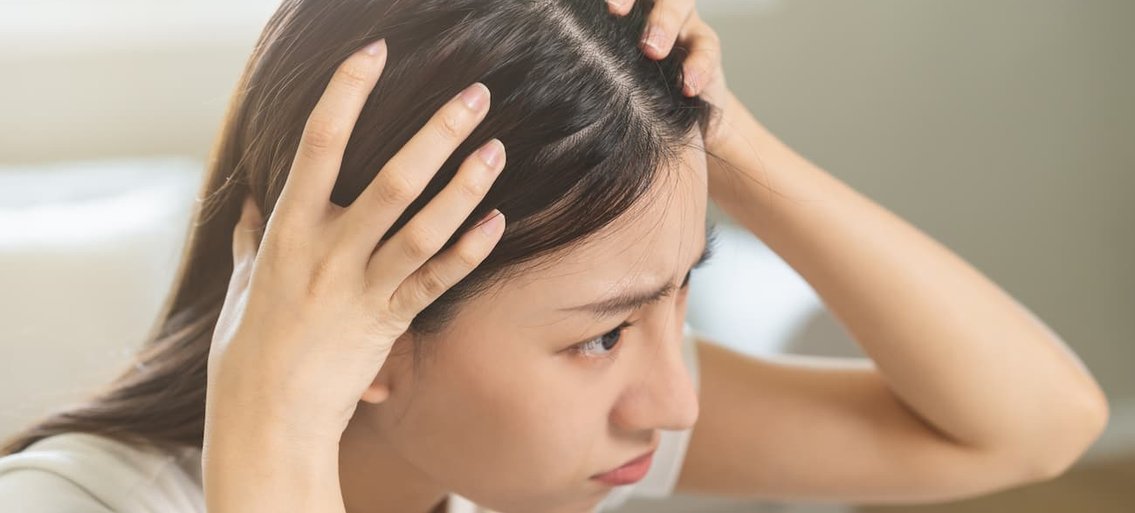 primo piano di una donna che esamina il suo cuoio capelluto