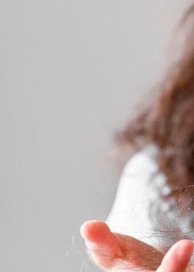 volto in primo piano di una donna che guarda una ciocca di capelli tra le mani