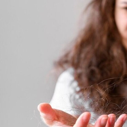 volto in primo piano di una donna che guarda una ciocca di capelli tra le mani